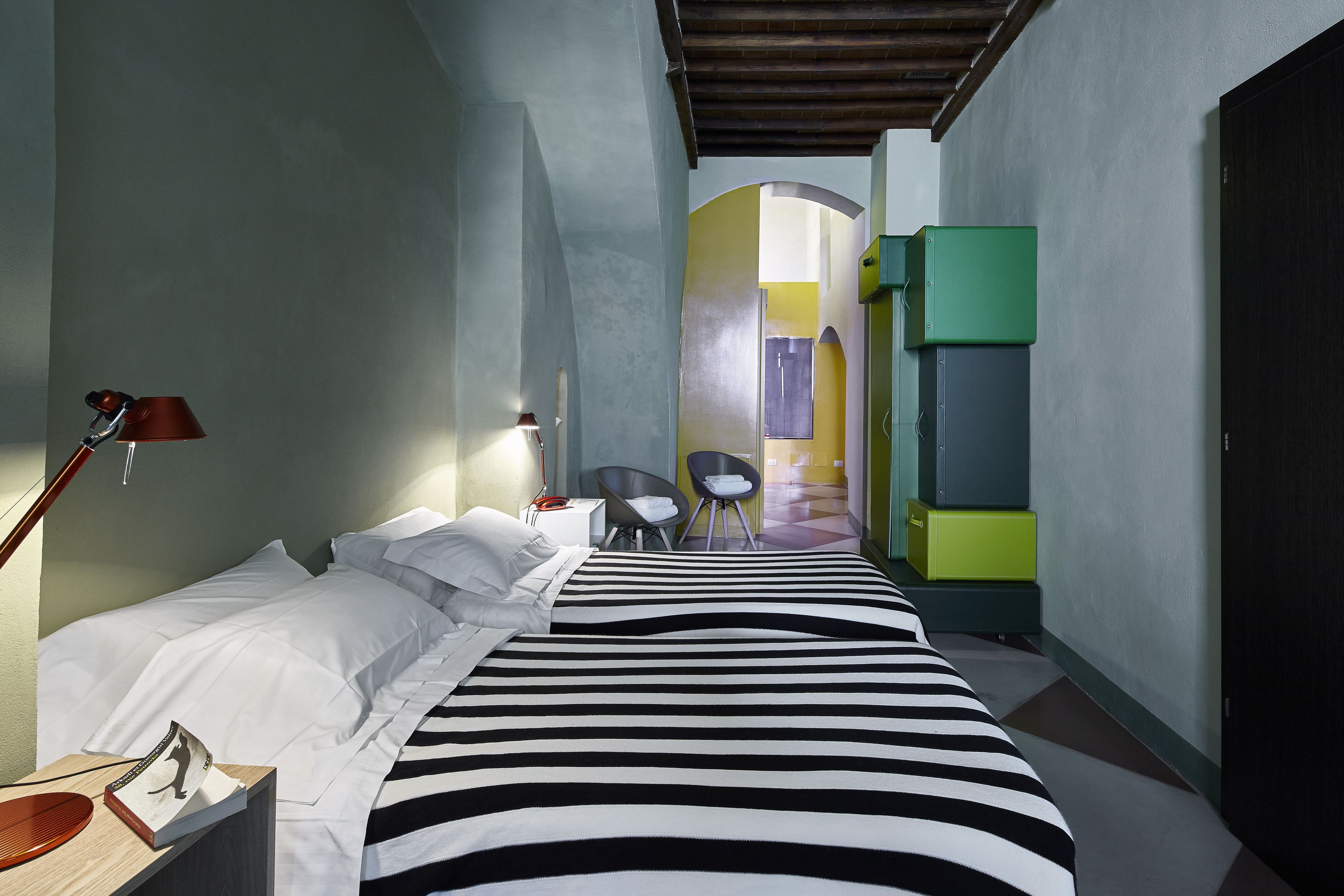 A hotel room with a bed, a desk, a chair, and a wardrobe.
