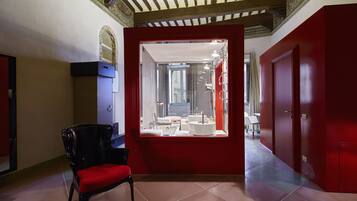Relax in a stylish room with a large window, a comfortable chair, and a modern bathroom featuring a sink and mirror.