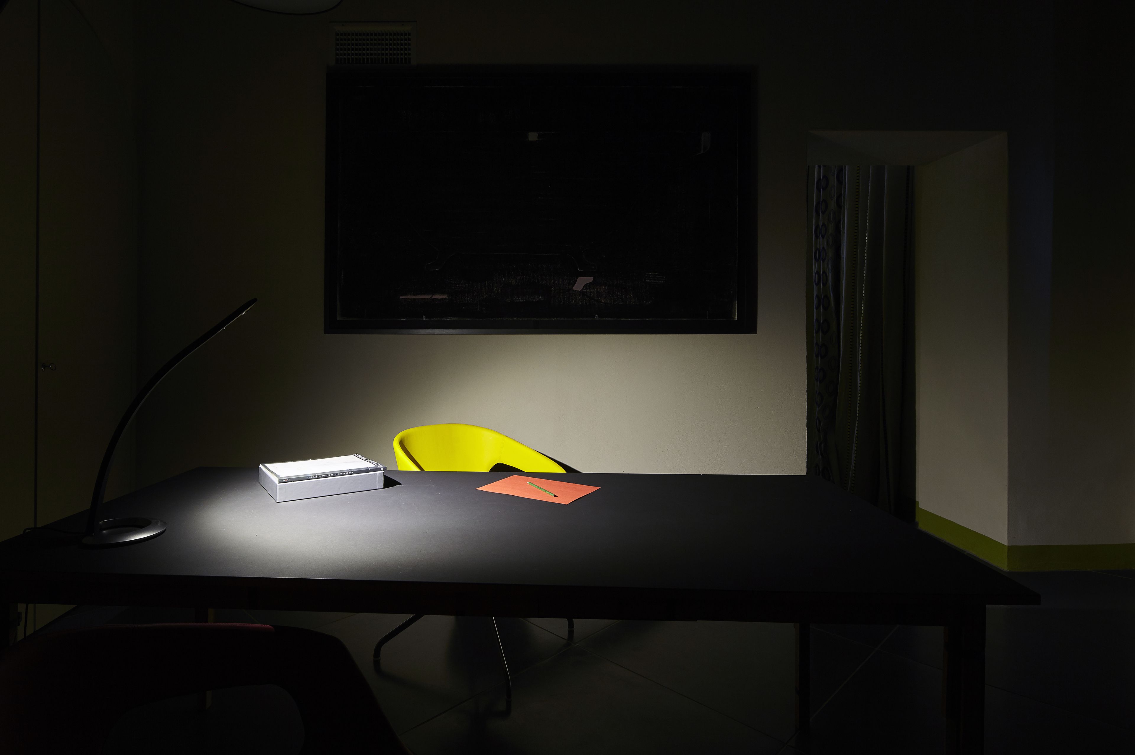 A conference room with a black table, a yellow chair, and a projector screen.