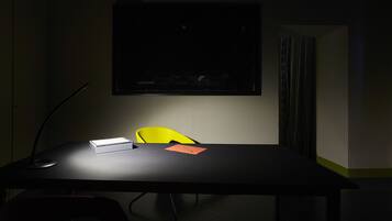 A conference room with a black table, a yellow chair, and a projector screen.