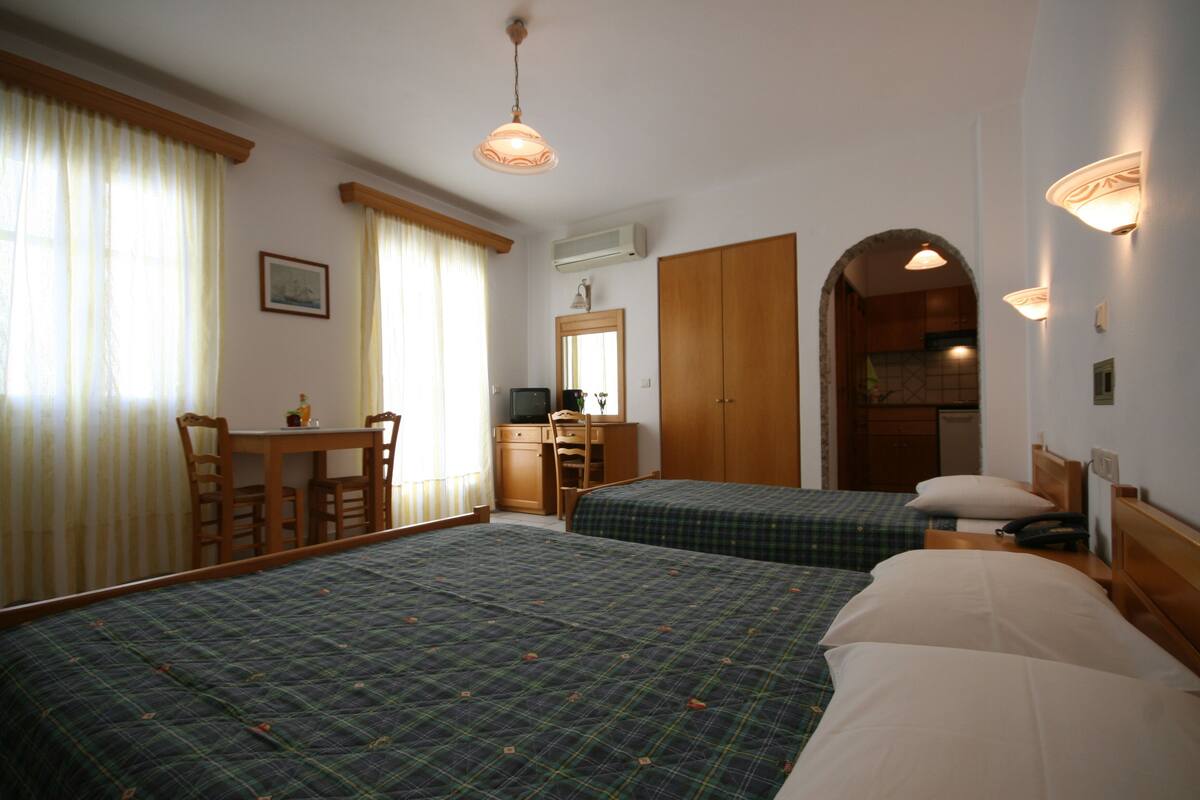 Une chambre d’hôtel avec deux lits, un bureau et une kitchenette.