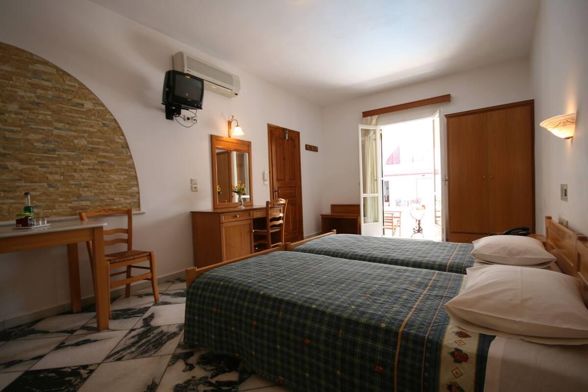 Une chambre avec deux lits, un bureau, une chaise, un miroir et une télévision.