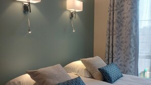 A hotel room with a bed, two wall-mounted lamps, and a window with curtains. - Hôtel le Relais de l'Abbaye (Saint-Evroult-Notre-Dame-du-Bois)