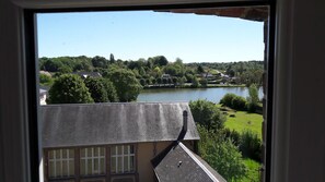 A view of a lake with surrounding greenery and buildings. - Hôtel le Relais de l'Abbaye (Saint-Evroult-Notre-Dame-du-Bois)