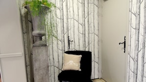 A corner room with a black chair, a white door, and a wall with a tree pattern. - Hôtel le Relais de l'Abbaye (Saint-Evroult-Notre-Dame-du-Bois)