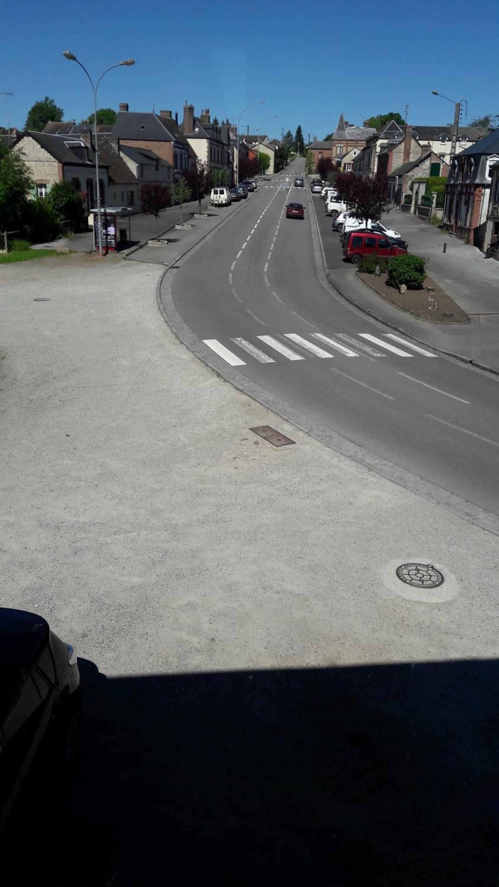 A street view with a pedestrian crossing, parked cars, and residential buildings.
