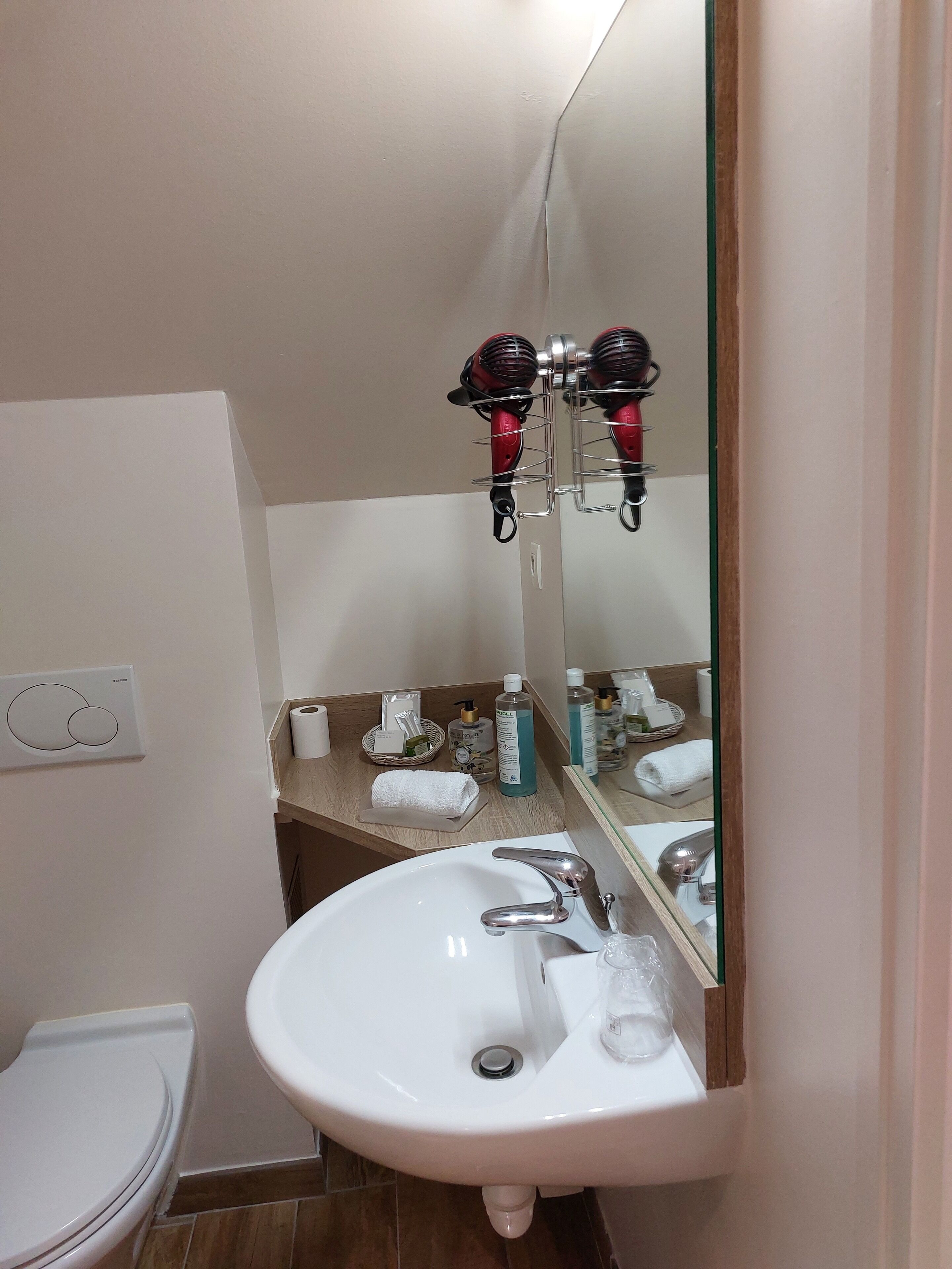 Un baño con un lavamanos blanco, un espejo y un secador de pelo montado en la pared.