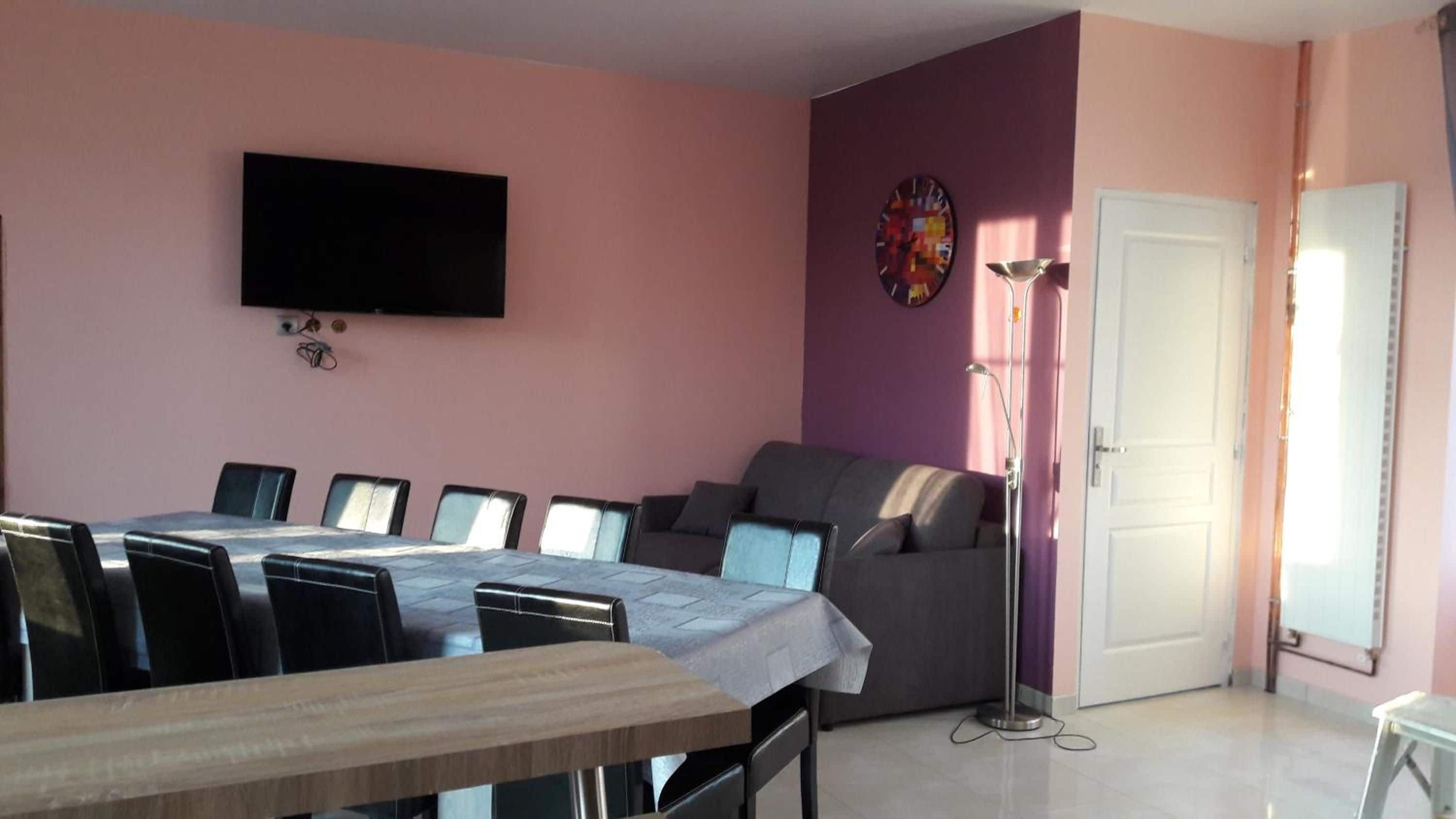 Une pièce comprenant une table à manger, des chaises, un canapé, un téléviseur et une porte.