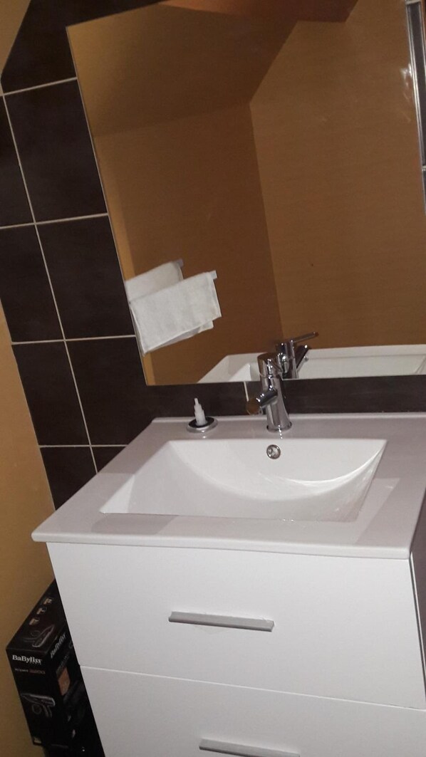 A bathroom with a white sink, a mirror, and a towel rack.