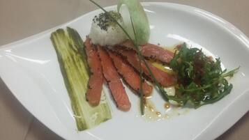 Een witte schaal met een gerecht bestaande uit rijst, zalm en groenten.
