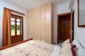 A bedroom with a bed, a wardrobe, and a door leading to another room.
