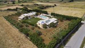 Una propietat residencial amb piscina, diversos edificis i camps circumdants.