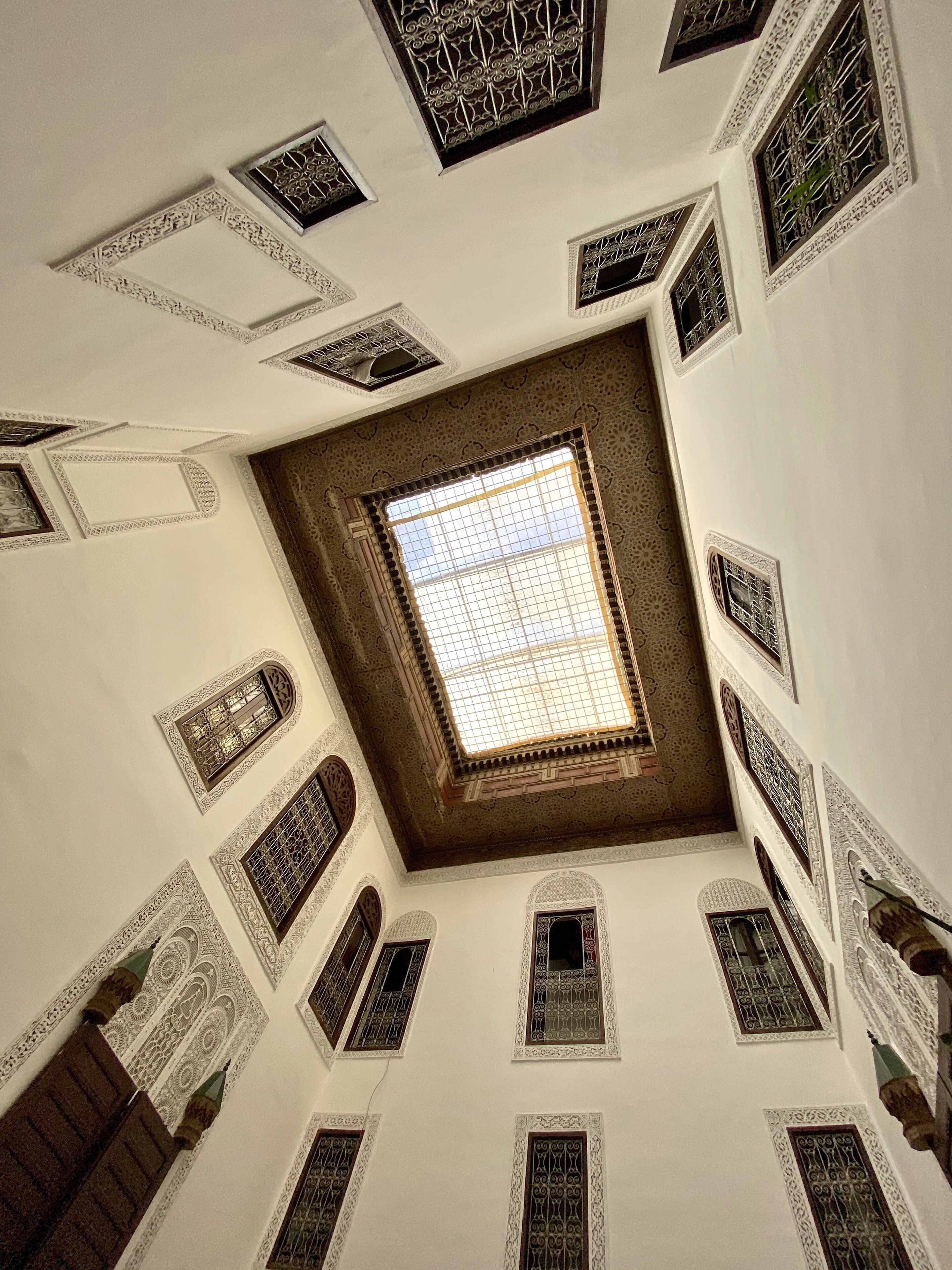 Una habitación con techos altos y detalles arquitectónicos elaborados, incluyendo celosías ornamentales en las ventanas y diseños geométricos en las paredes.