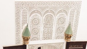 An ornate doorway with intricate patterns, a hanging lantern, and a patterned floor. - Riad Tizwa Fes (Fes)