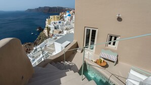A hotel with a pool, a staircase, and a view of the sea. - Ammos Oia Mansion (Santorini)