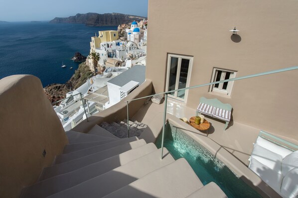 A hotel with a pool, a staircase, and a view of the sea. - Ammos Oia Mansion (Santorini)