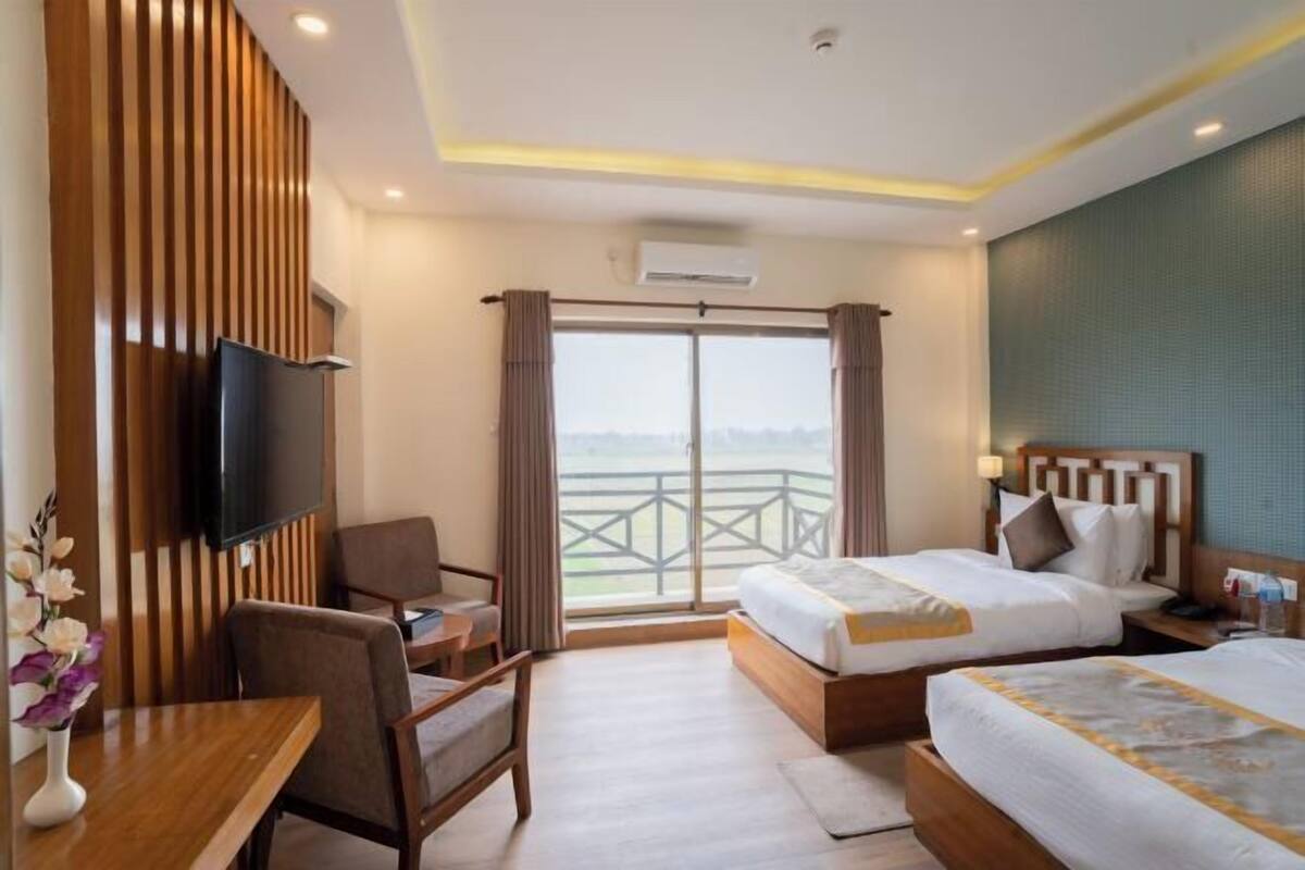 Ein Hotelzimmer mit Bett, Schreibtisch, Sessel, Fernseher und einem Balkon mit Aussicht.