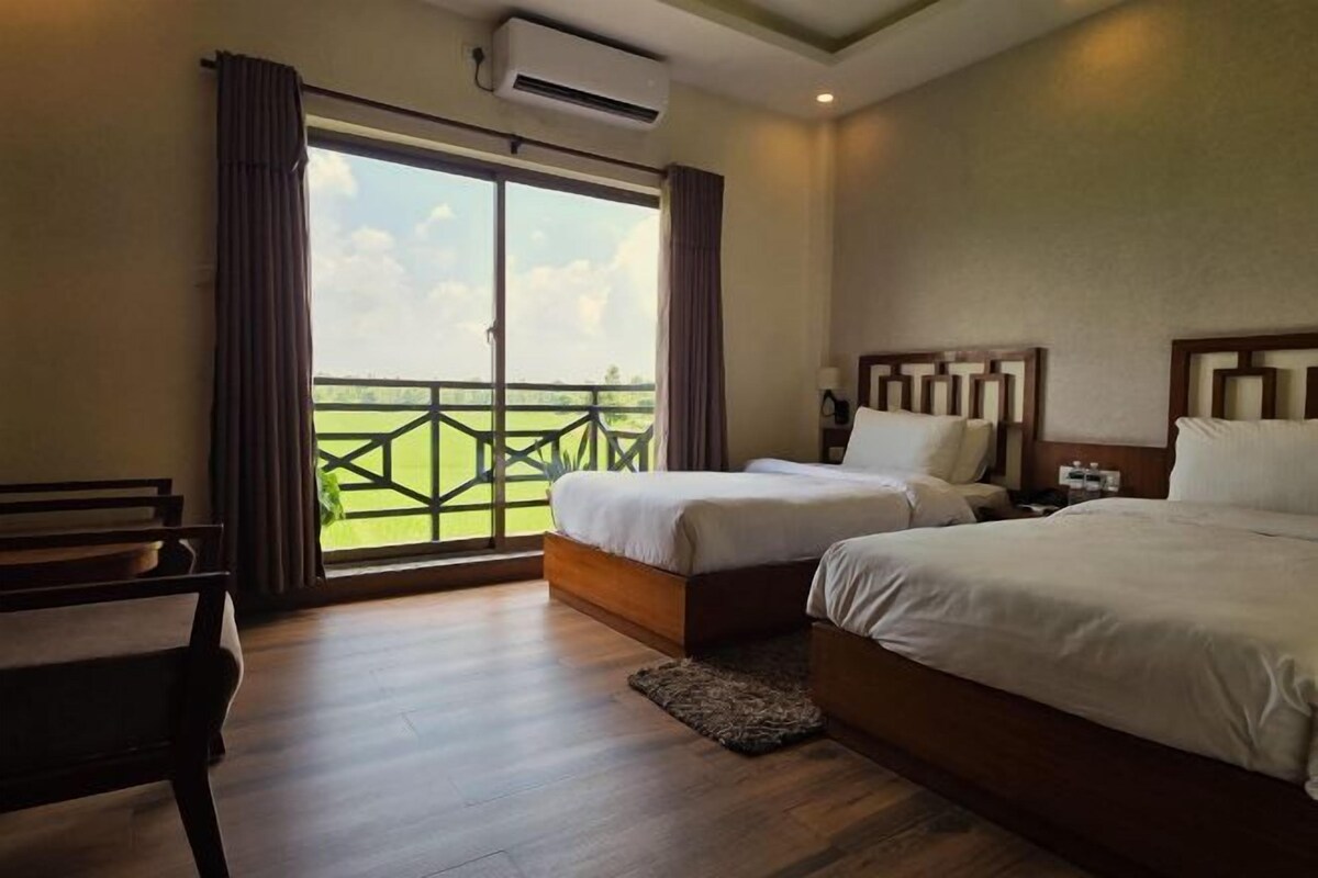 A hotel room with two beds, a desk, and a balcony with a view.