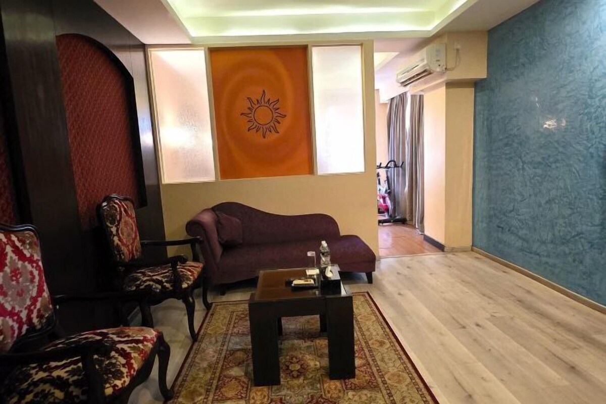 A living room with a sofa, chairs, a coffee table, and a decorative wall piece.