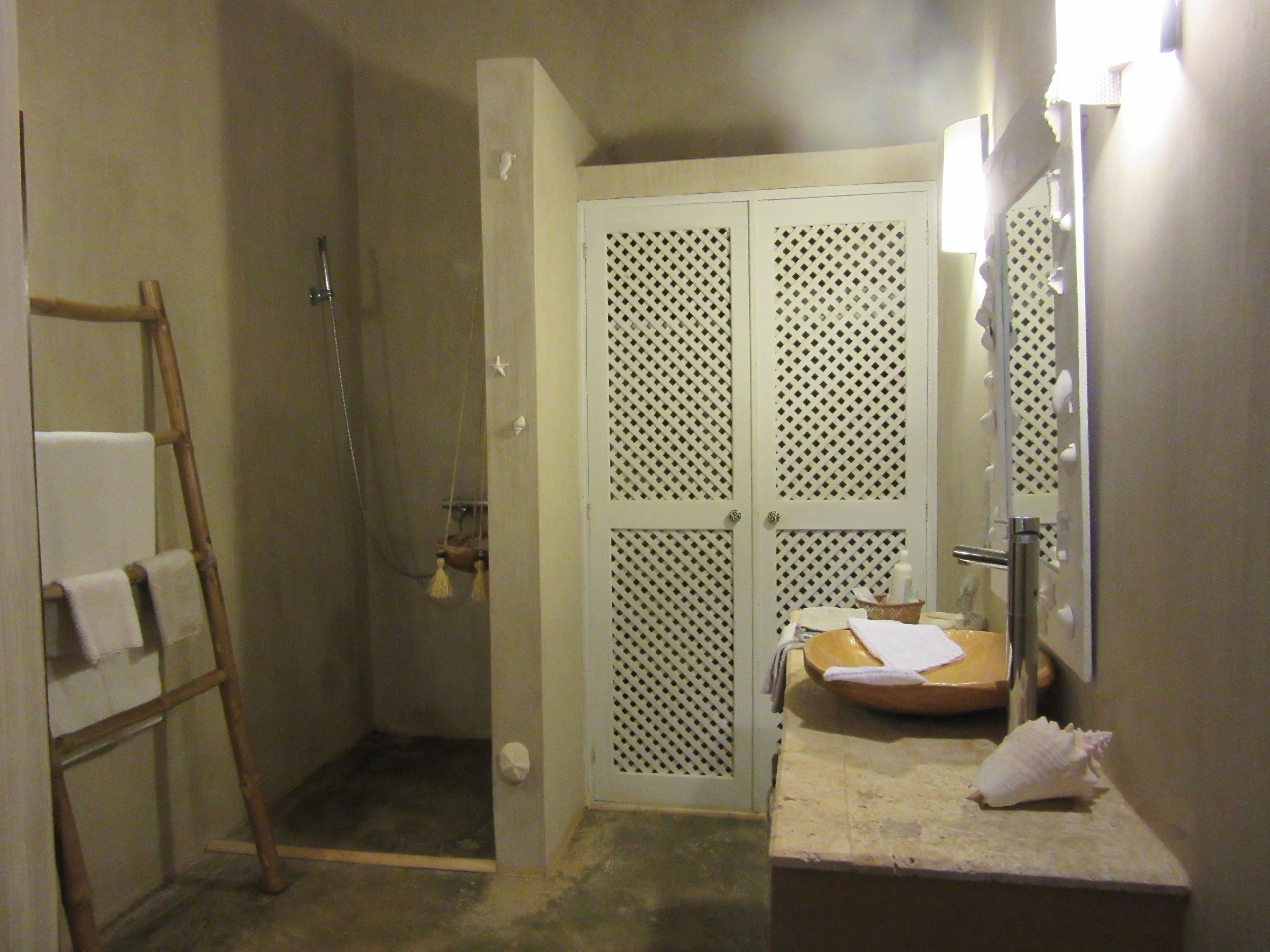 Une salle de bain avec une douche, un lavabo avec un miroir et un porte-serviettes.