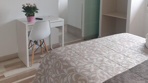 A bedroom with a bed, a desk with a chair, a television, and a wardrobe.