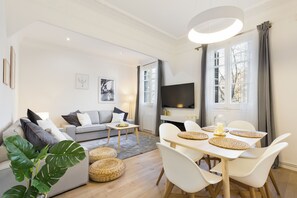 Uma sala de estar moderna com um sofá, uma mesa de jantar com cadeiras e uma televisão.