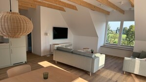 A modern loft-style room with a dining table, sofa, and TV. - Restaurant und Pension Zur Wildgans (Arendsee)