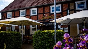 A building with a sign reading 'Zaw Wildways' and 'VELTINS' with outdoor seating and umbrellas. - Restaurant und Pension Zur Wildgans (Arendsee)