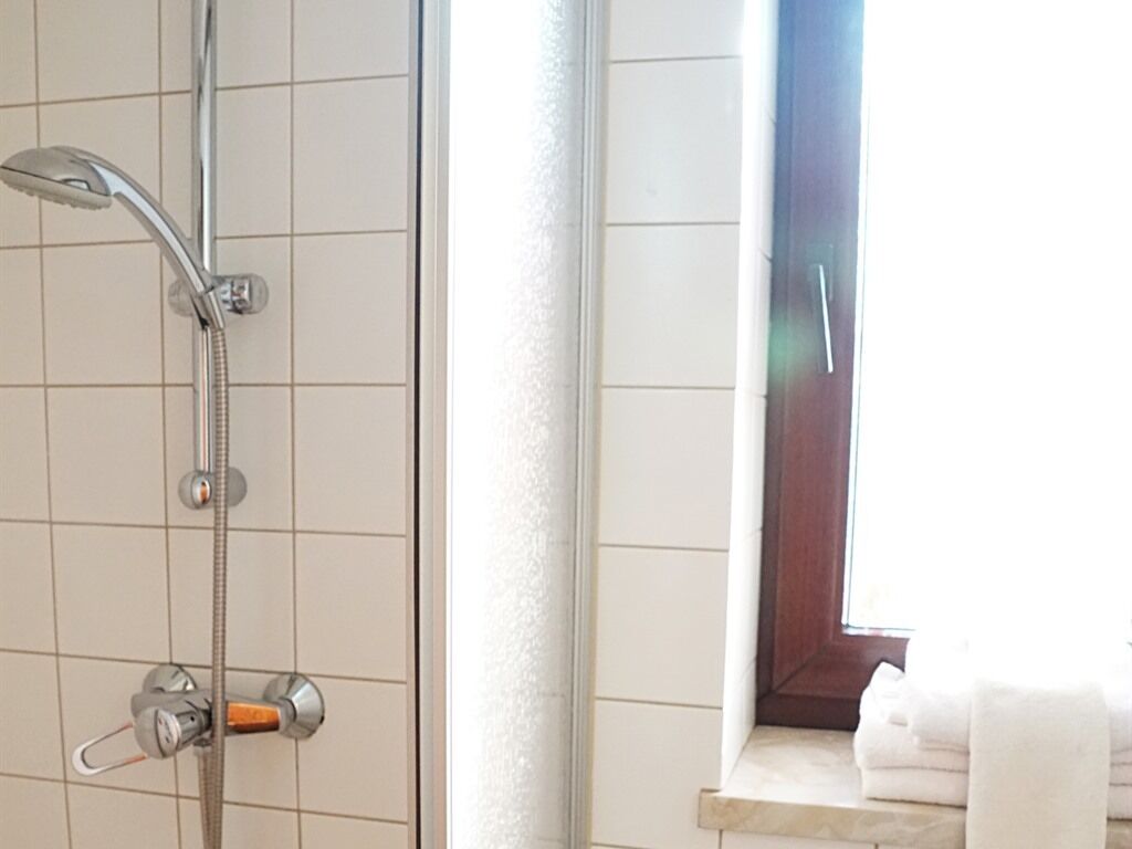 Un baño con ducha, ventana y perchero.