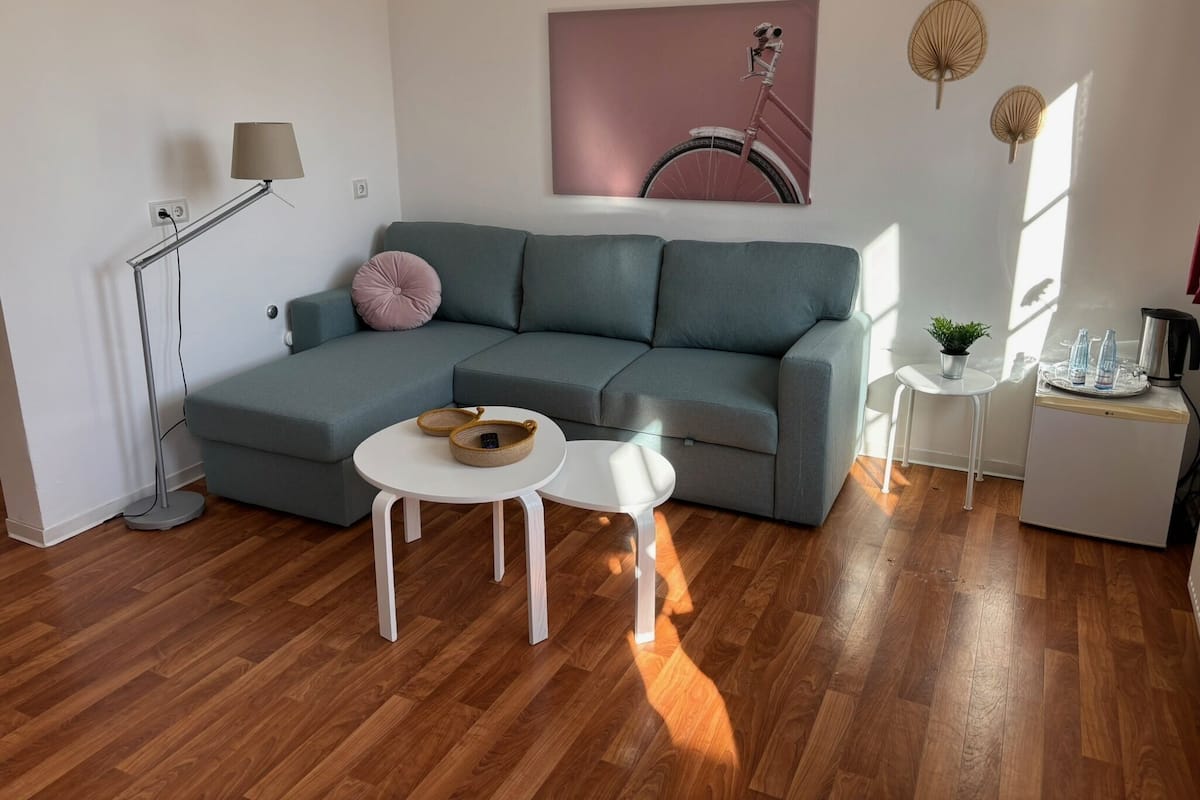 A modern living room with a grey sectional sofa, a small white table, a floor lamp, and a wall-mounted bicycle decoration.