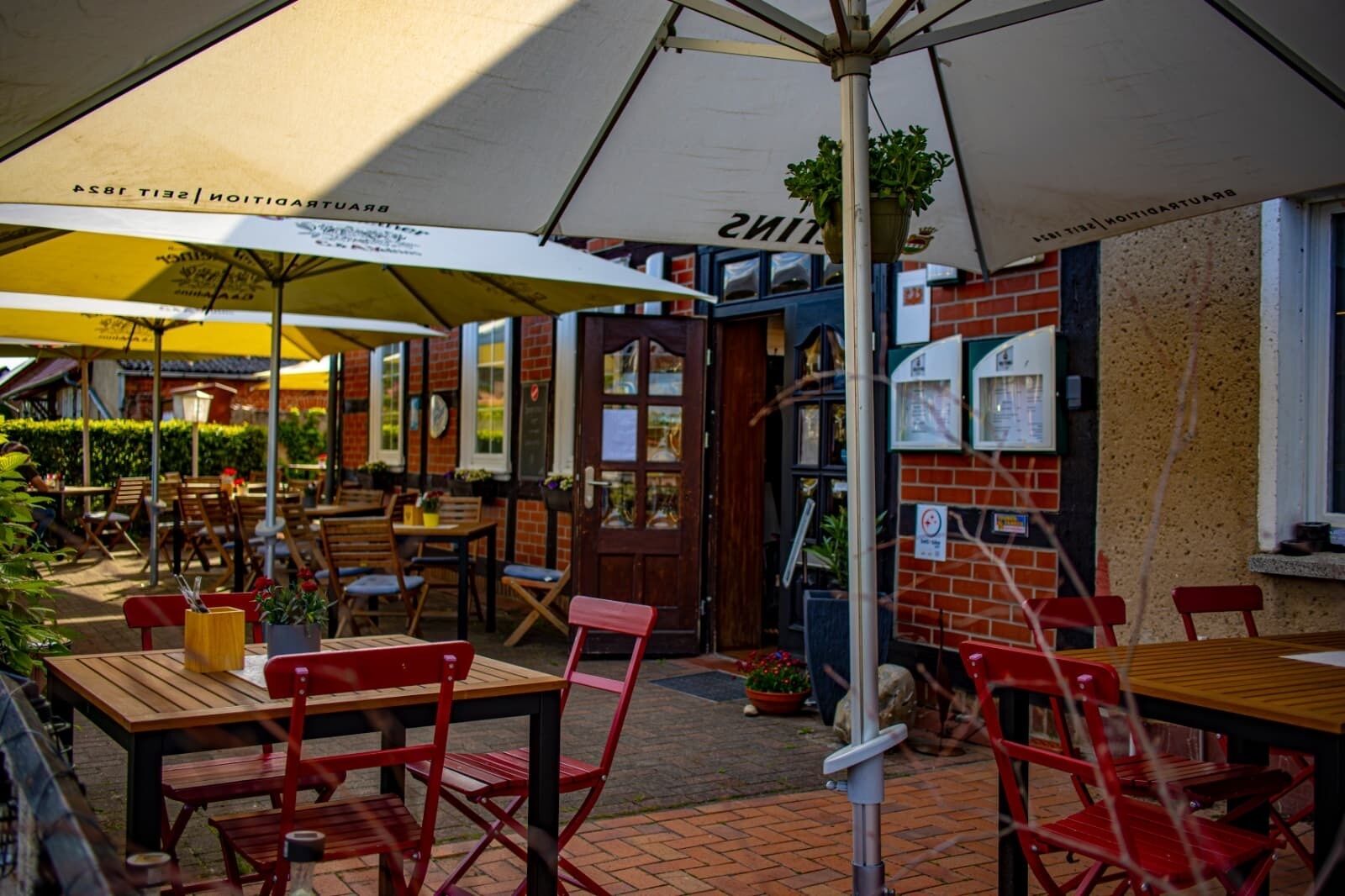 Un espace extérieur aménagé avec des tables, des chaises, des parasols et un mur en briques.