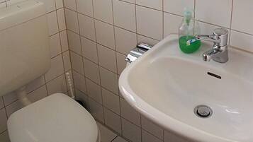Een badkamer met toilet, wastafel en een zeepdispenser.