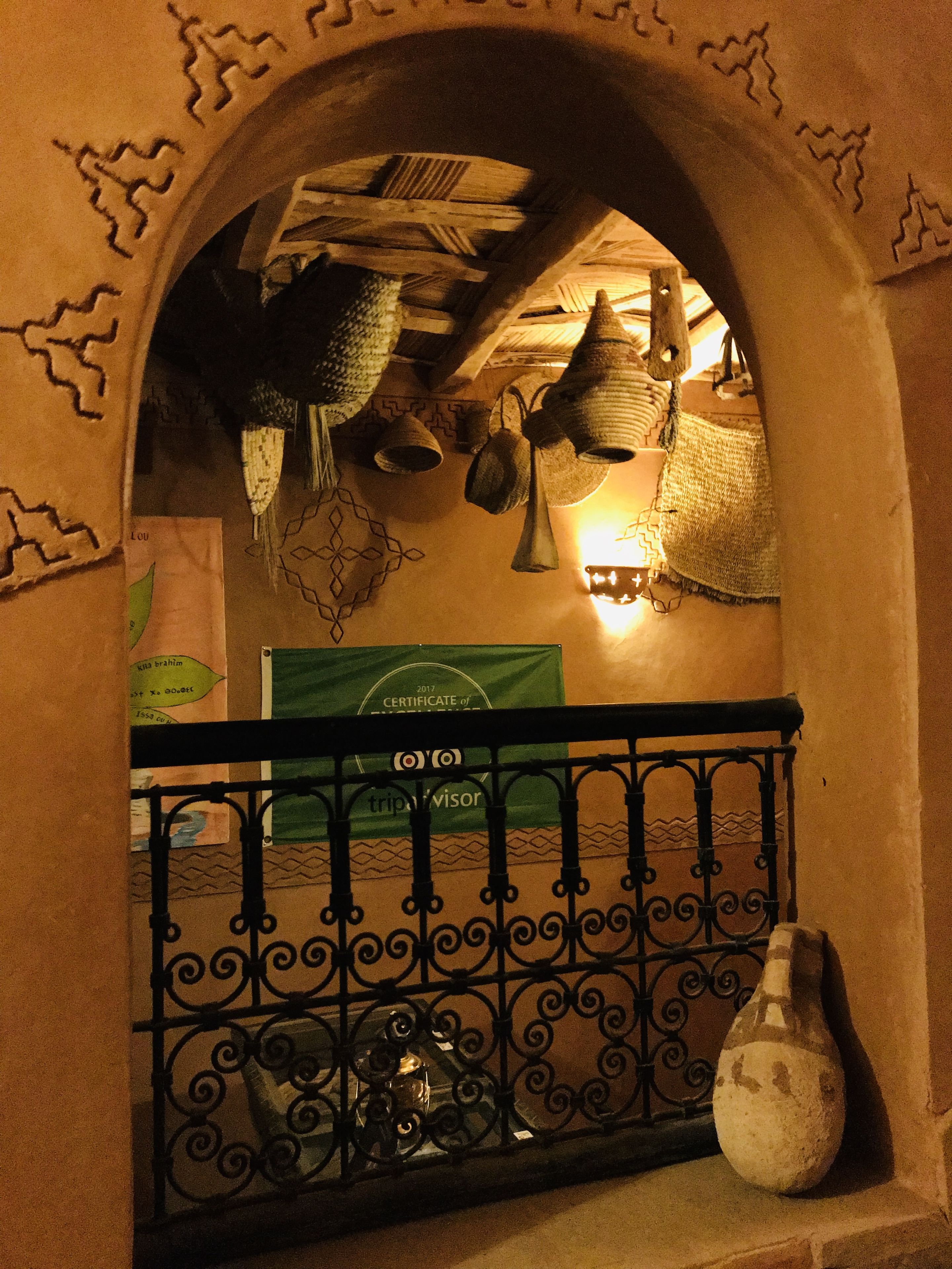 An arched doorway with a decorative railing, a certificate of achievement, and hanging lamps.