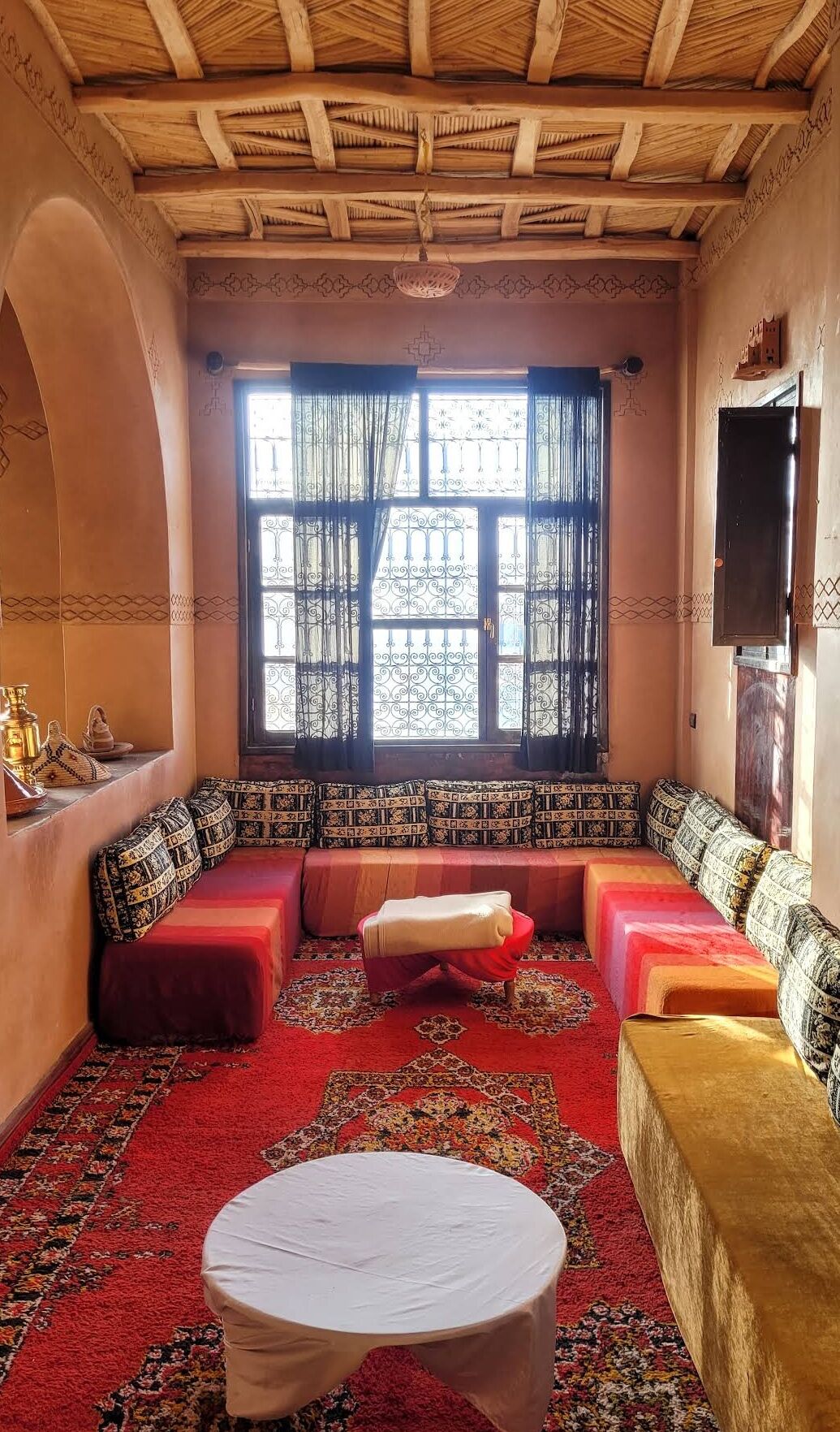 Une pièce chaleureuse avec une grande fenêtre, un ensemble de canapés, une petite table et un tapis décoratif.