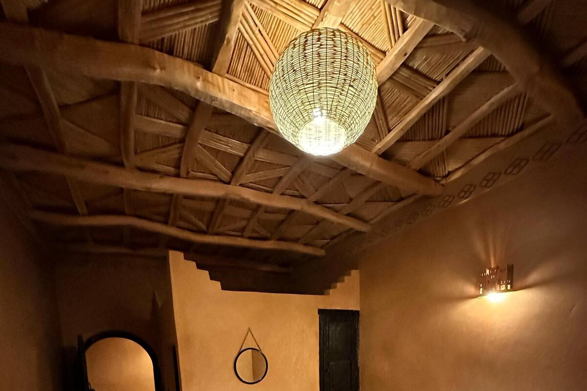 A cozy room with a bed, a small table, and a hanging light fixture.