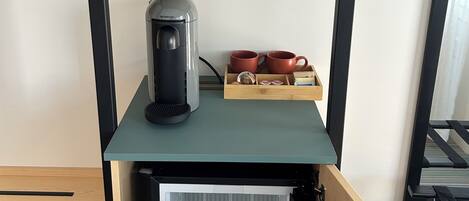 Ett litet, praktiskt pentry med en kaffebryggare, två muggar och ett litet kylskåp.