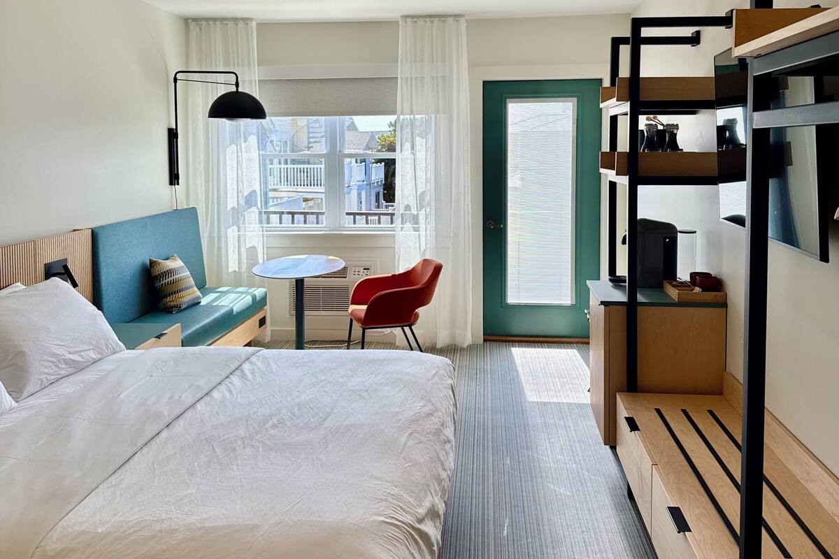 Habitación de hotel con cama, escritorio, silla, ventana con vistas y literas.