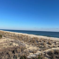 Na praia, areia branca, espreguiçadeiras, toalhas de praia