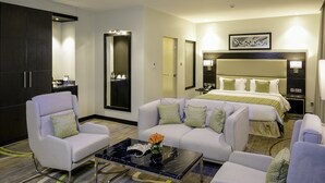Ein Hotelzimmer mit einem Bett, zwei Sesseln, einem Sofa, einem Couchtisch, einem großen Spiegel und einem Kleiderschrank.