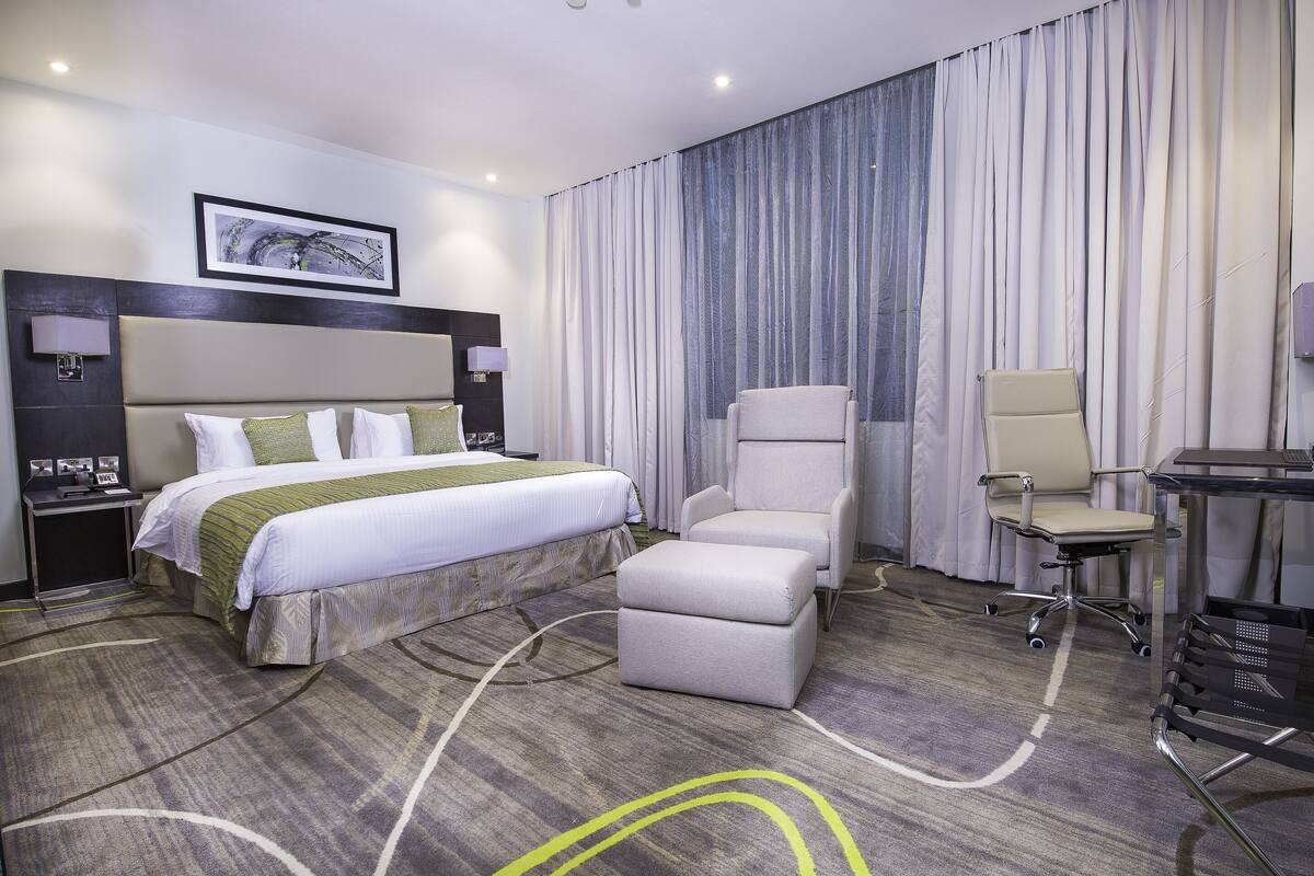 Habitación de hotel con una cama grande, un escritorio, una silla y una lámpara de escritorio.