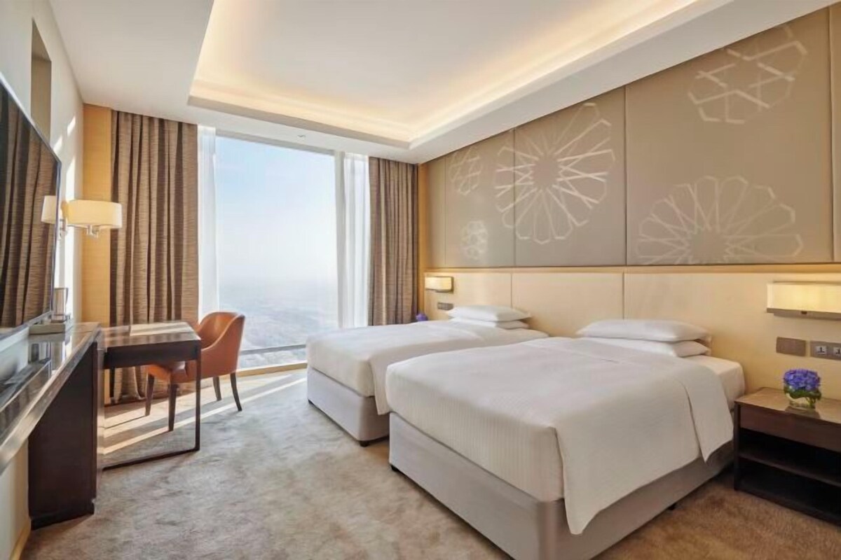 A hotel room with two beds, a desk, and a chair.