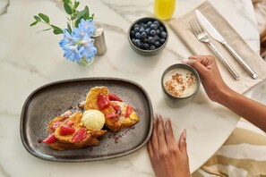 A breakfast setting with a plate of French toast, blueberries, and a scoop of ice cream.