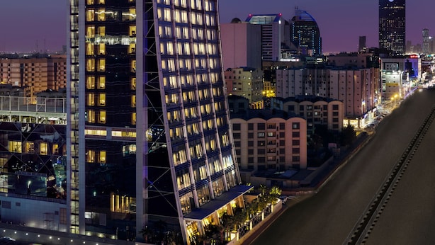 Un hôtel moderne doté d’une façade incurvée originale, de plusieurs étages et de fenêtres illuminées.