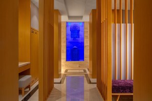 A hallway with wooden paneling, a bench, and a blue-lit water feature.