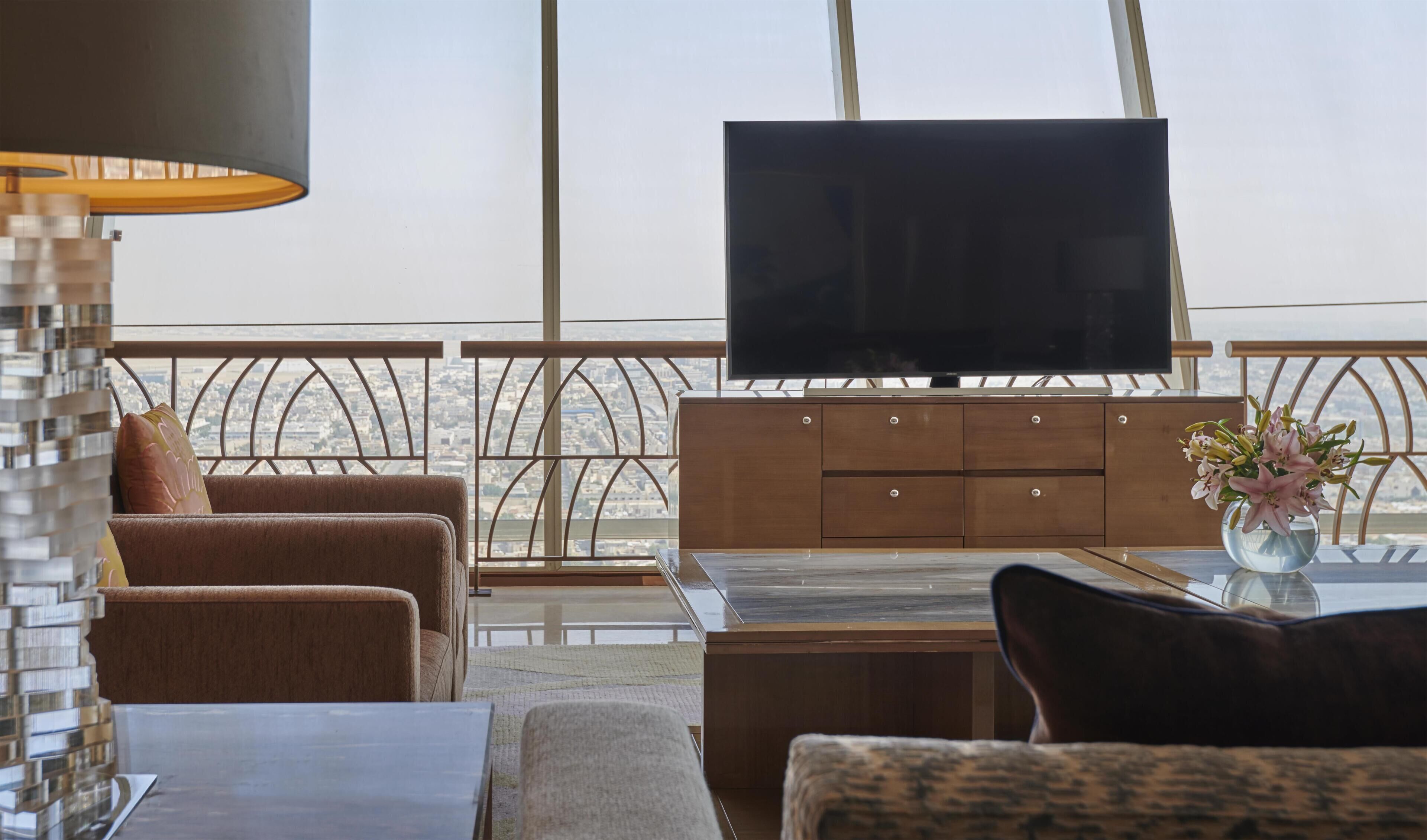 Una sala de estar moderna con un televisor de pantalla plana, armarios de madera y vistas a la ciudad.