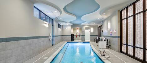 A swimming pool with a clear waterline, surrounded by tiled walls and a ceiling with a wavy design.