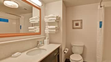 Un baño con lavamanos, espejo, toallero, inodoro y cortina de ducha.