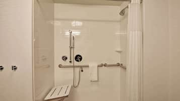 A walk-in shower with a grab bar, a handheld showerhead, and a towel rack.