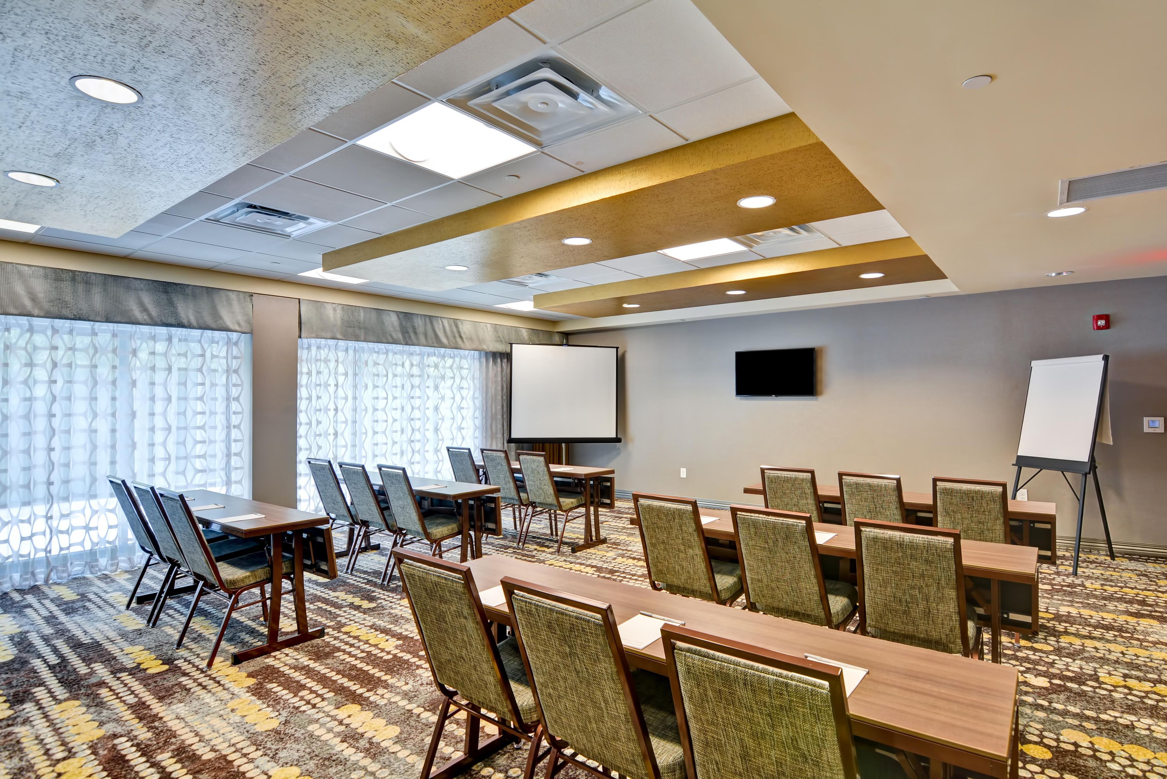 A conference room with a large table, chairs, a projector screen, and a whiteboard.