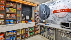 Zona de exhibición de aperitivos y dulces con diversos productos y una pizarra con el pronóstico del tiempo.
